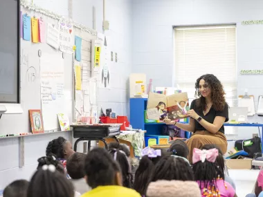 an MRC volunteer reading to a classroom of young students