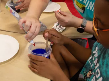 an student makes slime in a fun STEM activity with an MRC volunteer