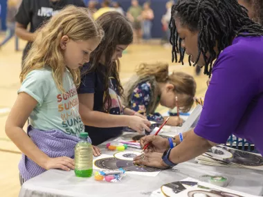 an MRC volunteer helps students with an activity at an MRC family engagement event